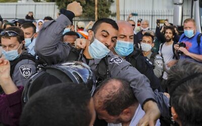 A police officer scuffles with Ofer Cassif, a Jewish member of the predominantly Arab Joint List party, during a demonstration in East Jerusalem on April 9, 2021 (AHMAD GHARABLI / AFP)