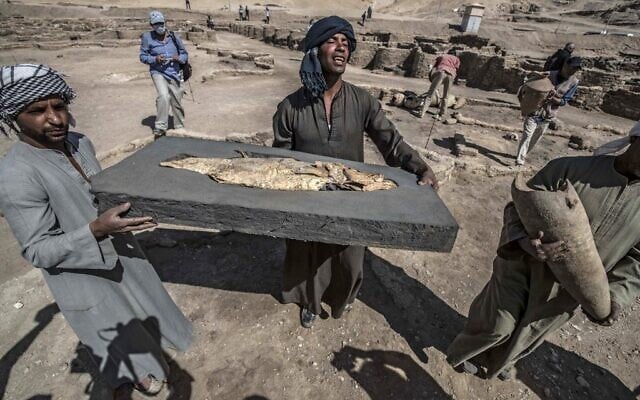 A picture taken on April 10, 2021, shows workers carrying a fish covered in gold uncovered at the archaeological site of a 3,000 year old city, dubbed The Rise of Aten, dating to the reign of Amenhotep III, uncovered by the Egyptian mission near Luxor (Khaled DESOUKI / AFP) A picture taken on April 10, 2021, shows workers carrying a fish covered in gold uncovered at the archaeological site of a 3,000 year old city, dubbed The Rise of Aten, dating to the reign of Amenhotep III, uncovered by the Egyptian mission near Luxor (Khaled DESOUKI / AFP)