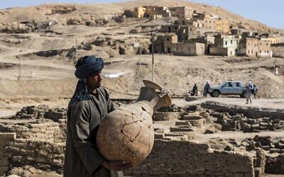 A picture taken on April 10, 2021, shows a worker carrying a pot at the archaeological site of a 3,000 year old city, dubbed The Rise of Aten, dating to the reign of Amenhotep III, uncovered by the Egyptian mission near Luxor. (Khaled Desouki/AFP)