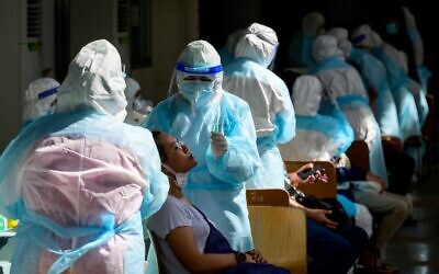 A medical worker wearing PPE (personal protective equipment) takes a swab sample from a woman during a mass testing event at a sport complex in Bangkok on April 17, 2021, after the recent outbreak of coronavirus cases in Thailand. (Mladen ANTONOV / AFP)