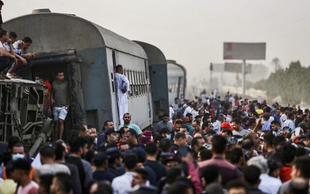 People gather by an overturned train carriage at the scene of a railway accident in the city of Toukh in Egypt's central Nile Delta province of Qalyubiya on April 18, 2021. (Ayman AREF / AFP) People gather by an overturned train carriage at the scene of a railway accident in the city of Toukh in Egypt's central Nile Delta province of Qalyubiya on April 18, 2021. (Ayman AREF / AFP)