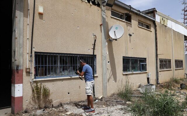 A man films a building damaged by rockets fired from the Gaza Strip, in the kibbutz Kissufim in southern Israel on April 24, 2021 (JACK GUEZ / AFP)