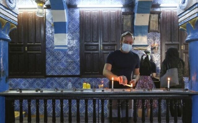 A Tunisian Jewish pilgrim lights a candle on the first day of the annual pilgrimage to the Ghriba Synagogue, the oldest Jewish monument built in Africa, on April 26, 2021 in the Mediterranean Tunisian resort island of Djerba. (Photo by FATHI NASRI / AFP)
