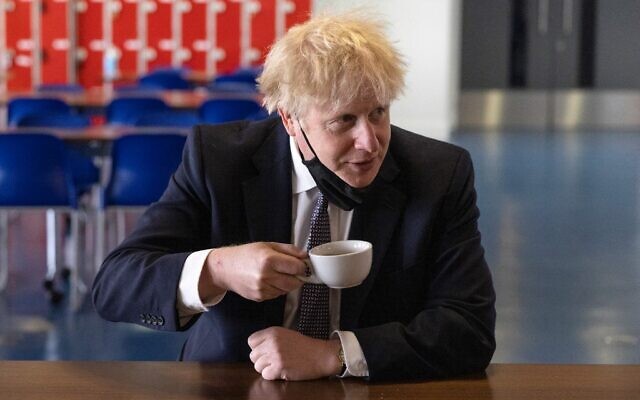 Britain's Prime Minister Boris Johnson, holds a cup of coffee as he speaks with pupils after taking part in a science lesson at King Solomon Academy in London, on April 29, 2021. (Dan Kitwood / POOL / AFP)