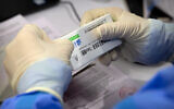 A worker opens a package of coronavirus vaccine made by a Sinopharm subsidiary during a COVID-19 vaccination session for resident foreign journalists at a vaccination center in Beijing, Tuesday, March 23, 2021. (AP Photo/Mark Schiefelbein)
