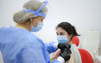A woman gets an AstraZeneca vaccine at a vaccination center in Bucharest, Romania, Wednesday, April 7, 2021. (AP Photo/Vadim Ghirda)