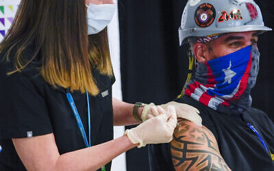 Illustrative: A nurse inoculates Local 28 Sheet Metal Worker Demetrius Buttelman with the first dose of the Pfizer vaccine during a news conference at the Belmont Park in Elmont, New York, April 14, 2021. (AP Photo/Mary Altaffer, Pool, File) Illustrative: A nurse inoculates Local 28 Sheet Metal Worker Demetrius Buttelman with the first dose of the Pfizer vaccine during a news conference at the Belmont Park in Elmont, New York, April 14, 2021. (AP Photo/Mary Altaffer, Pool, File)