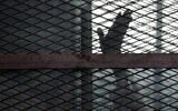 Illustrative: A member of the Muslim Brotherhood waves his hand from a defendants cage in a courtroom in Torah prison, southern Cairo, Egypt, August 22, 2015. (AP Photo/Amr Nabil, File)