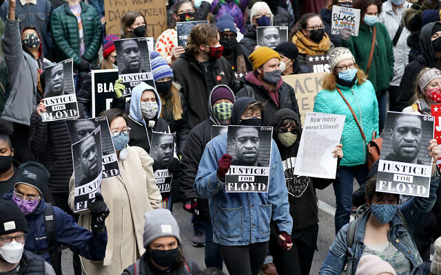 People hold signs as they march near the Hennepin County Government Center during a rally in Minneapolis on Monday, April 19, 2021, after the murder trial against former Minneapolis police Officer Derek Chauvin advanced to jury deliberations. (AP Photo/Julio Cortez)