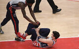Washington Wizards forward Deni Avdija, bottom, reacts after he was injured during the first half of an NBA basketball game against the Golden State Warriors, April 21, 2021, in Washington. Also seen is Wizards center Jordan Bell (7). (AP Photo/Nick Wass)
