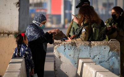 Illustrative: Israeli soldiers check a Palestinian woman as she waits to cross the Qalandiya checkpoint between the West Bank city of Ramallah and Jerusalem, April 23, 2021. (AP/Majdi Mohammed)