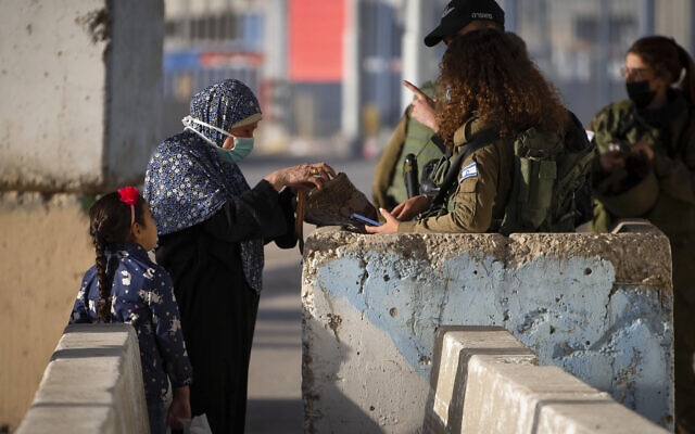 Illustrative: Israeli soldiers check a Palestinian woman as she waits to cross the Qalandiya checkpoint between the West Bank city of Ramallah and Jerusalem, April 23, 2021. (AP/Majdi Mohammed) Illustrative: Israeli soldiers check a Palestinian woman as she waits to cross the Qalandiya checkpoint between the West Bank city of Ramallah and Jerusalem, April 23, 2021. (AP/Majdi Mohammed)