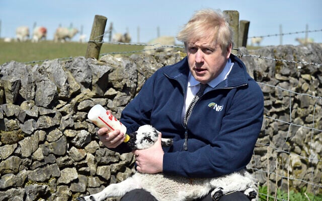 Britain's Prime Minister Boris Johnson feeds a lamb at Moor Farm in Stoney Middleton, England on April 23, 2021. (AP/Rui Vieira, Pool) Britain's Prime Minister Boris Johnson feeds a lamb at Moor Farm in Stoney Middleton, England on April 23, 2021. (AP/Rui Vieira, Pool)