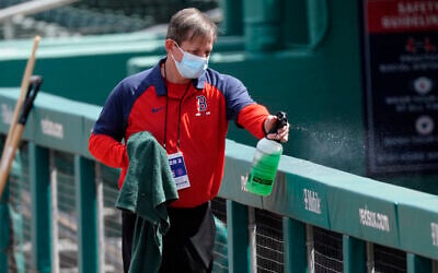 A Boston Red Sox staff member disinfects the railing in front of the visitor's dugout before a spring training baseball game between the Atlanta Braves and Boston Red Sox, March 10, 2021, in Fort Myers, Florida. (AP/John Bazemore) A Boston Red Sox staff member disinfects the railing in front of the visitor's dugout before a spring training baseball game between the Atlanta Braves and Boston Red Sox, March 10, 2021, in Fort Myers, Florida. (AP/John Bazemore)