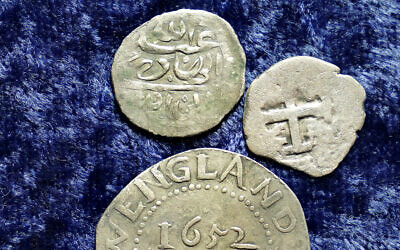 A 17th century Arabian silver coin, top, that research shows was struck in 1693 in Yemen, rests near an Oak Tree Shilling minted in 1652 by the Massachusetts Bay Colony, below, and a Spanish half real coin from 1727, right, on a table, in Warwick, Rhode Island, March 11, 2021 (AP Photo/Steven Senne)