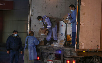 Illustrative: Palestinians from Gaza's health ministry unload boxes of Russian Sputnik V vaccine doses sent by the United Arab Emirates, at the Rafah crossing in the southern Gaza Strip, on March 11, 2021. (Abed Rahim Khatib/Flash90)