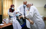 Palestinian medical workers receive a vaccine against the coronavirus at a medical center in the West Bank city of Dura on March 21, 2021. (Wisam Hashlamoun/FLASH90)