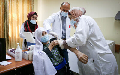Palestinian medical workers receive a vaccine against the coronavirus at a medical center in the West Bank city of Dura on March 21, 2021. (Wisam Hashlamoun/FLASH90)