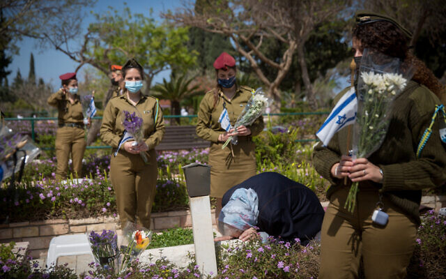 Israeli soldiers lay flowers and Israeli flags on the graves of fallen soldiers at the Kiryat Shaul Military Cemetery on April 13, 2021, ahead of Israeli Memorial Day. (Miriam Alster/Flash90) Israeli soldiers lay flowers and Israeli flags on the graves of fallen soldiers at the Kiryat Shaul Military Cemetery on April 13, 2021, ahead of Israeli Memorial Day. (Miriam Alster/Flash90)