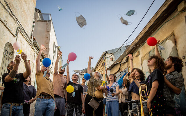 Israelis throwing face masks as they celebrate the end of the mask mandate outdoors in Jerusalem, on April 18, 2021. (Yonatan Sindel/Flash90)