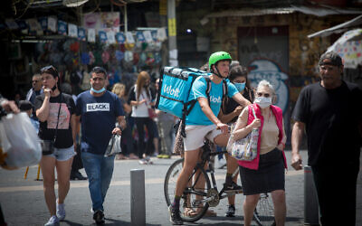 Israelis, some wearing protective face masks and some not, on the streets of Tel Aviv, April 21, 2021. (Miriam Alster/ FLASH90)