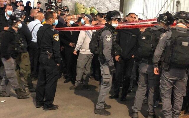 Police officers and onlookers at the scene of a deadly shooting in the northern town of Deir al-Asad, April 9, 2021. (Israel Police) Police officers and onlookers at the scene of a deadly shooting in the northern town of Deir al-Asad, April 9, 2021. (Israel Police)