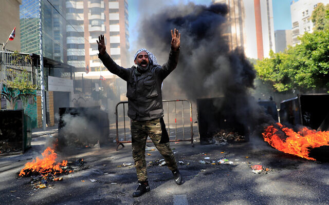 A man shouts slogans in front of burning tires and garbage containers during a protest against the increase in prices of consumer goods and the crash of the local currency, in Beirut, Lebanon, March 16, 2021. (AP Photo/Hussein Malla) A man shouts slogans in front of burning tires and garbage containers during a protest against the increase in prices of consumer goods and the crash of the local currency, in Beirut, Lebanon, March 16, 2021. (AP Photo/Hussein Malla)