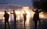 Nationalist youths gesture toward a police line blocking a road near the Peace Wall in West Belfast, Northern Ireland, April 8, 2021. (AP Photo/Peter Morrison)