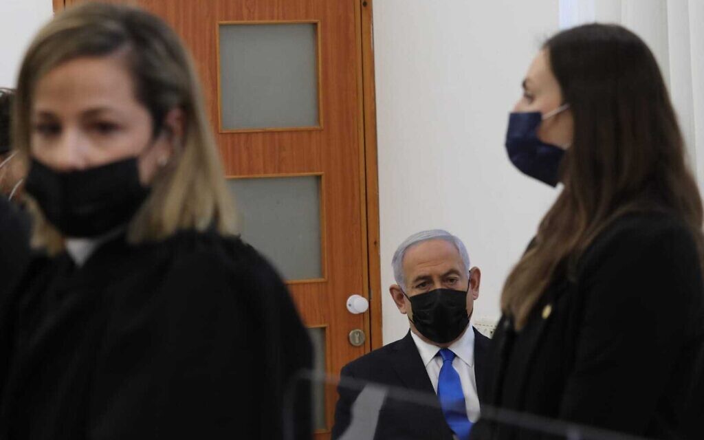Prime Minister Benjamin Netanyahu sits alone in the back bench of the Jerusalem District Court and scribbles notes as Liat Ben Ari begins her speech, March 5, 2021. (Oren Ben Hakoon/Pool)