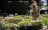 An Israeli soldier places flowers on the graves of fallen Israeli soldiers at the Mount Herzl military cemetery hours before the start of Memorial Day, in Jerusalem on April 20, 2020. (Yonatan Sindel/Flash90)