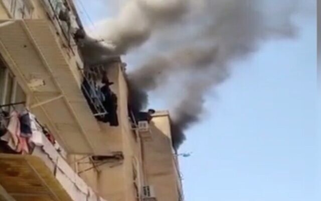 Screen capture from video of a boy, 12, leaning out of window during a fire at an apartment in Rishon Lezion, April 28, 2021. (Channel 12 News) Screen capture from video of a boy, 12, leaning out of window during a fire at an apartment in Rishon Lezion, April 28, 2021. (Channel 12 News)