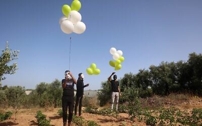 Masked Palestinians prepare to launch incendiary balloons across the northern Gaza border toward Israel, on May 8, 2021. (MOHAMMED ABED / AFP)