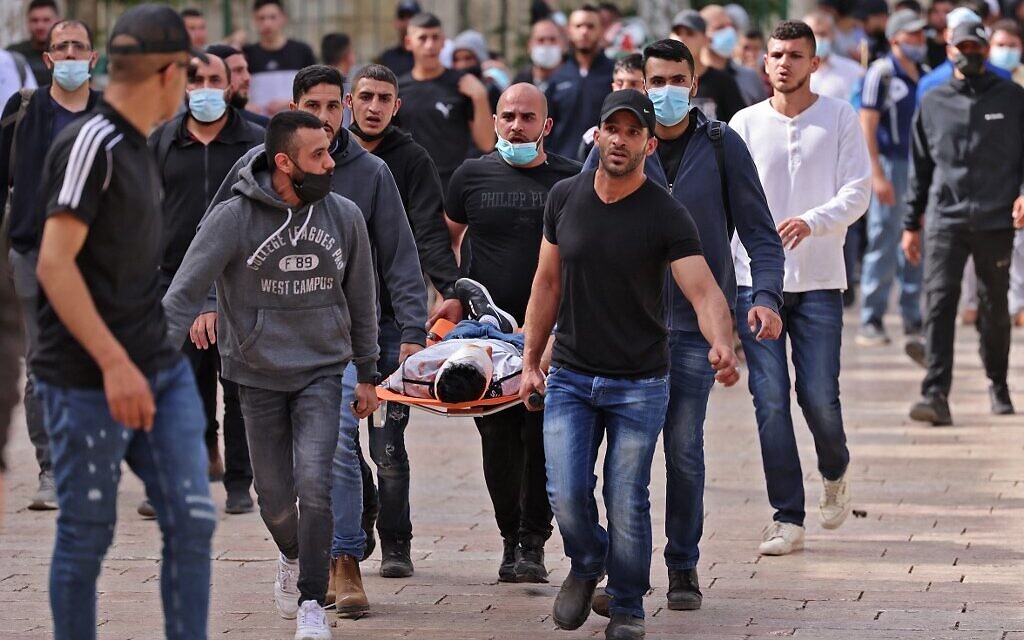 Palestinians evacuate a wounded protester amid clashes with Israeli security forces in Jerusalem's Old City on Jerusalem Day, May 10, 2021. (Photo by EMMANUEL DUNAND / AFP)