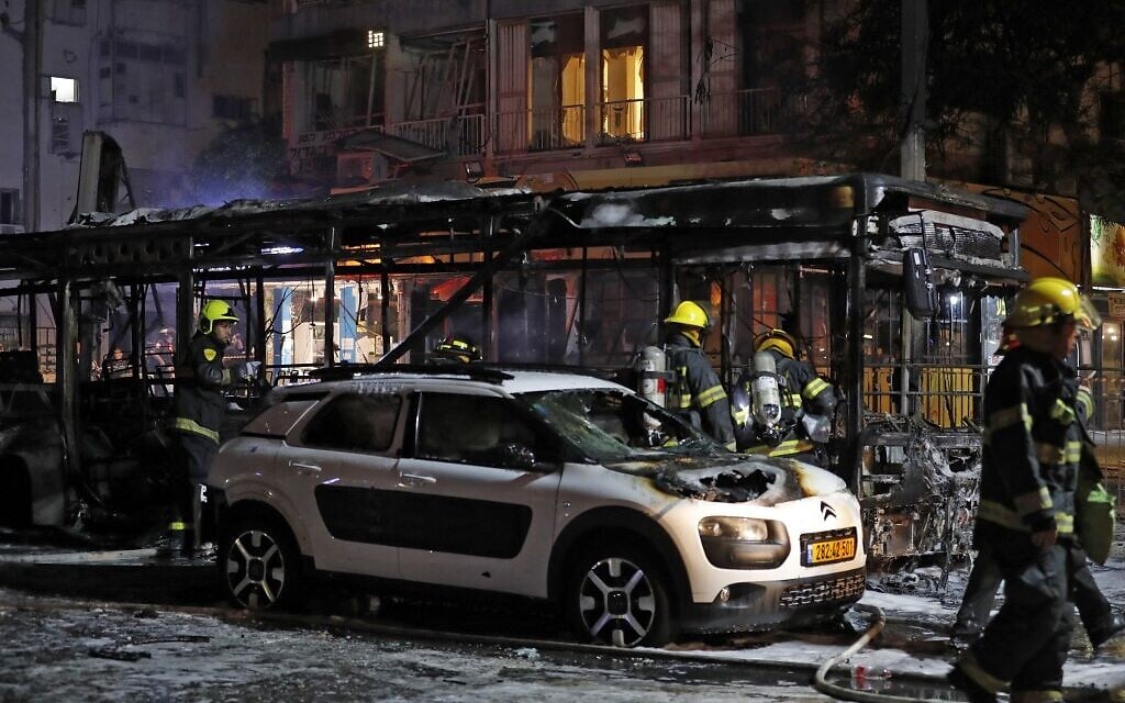 Firefighters near damaged vehicles in the city of Holon near Tel Aviv, on May 11, 2021, after rockets are launched at Israel from the Gaza Strip (Ahmad GHARABLI / AFP)
