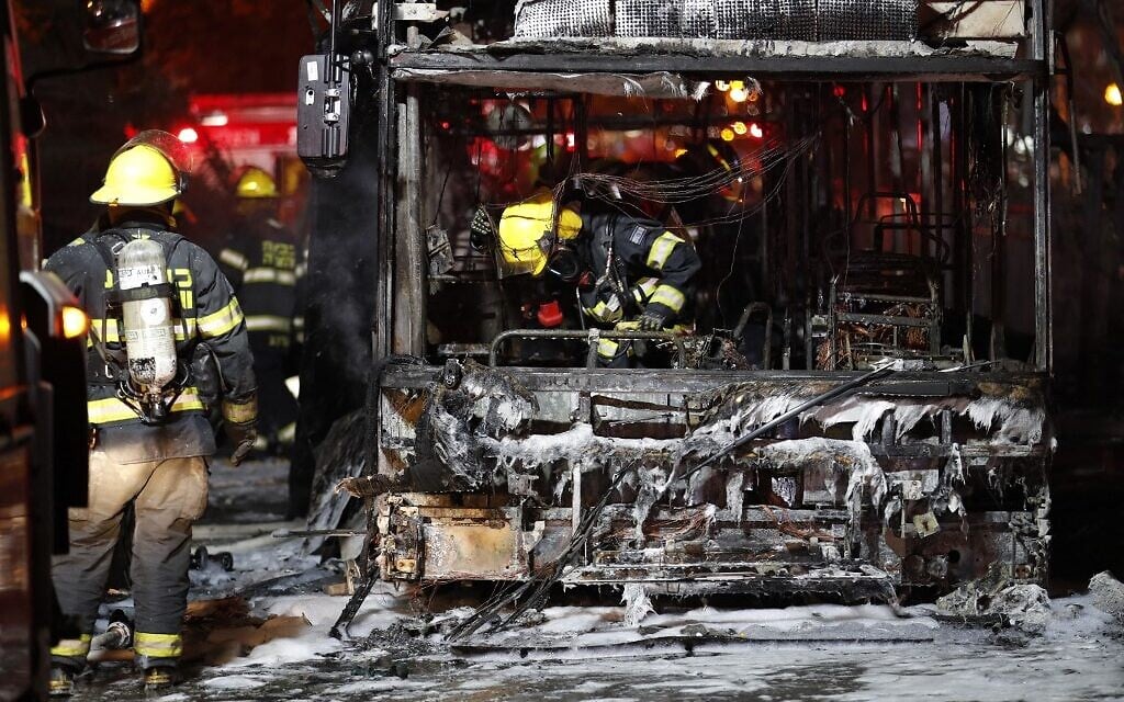 Firefighters examine a bus in the town of Holon near Tel Aviv, on May 11, 2021, that was hit by rockets fired from Gaza (Ahmad GHARABLI / AFP)