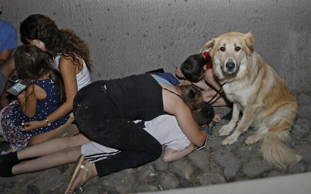 Israelis take cover under a bridge at the entrance of the central city of Tel Aviv, on May 11, 2021, after rockets were launched towards Israel from the Gaza Strip (Gil COHEN-MAGEN / AFP)