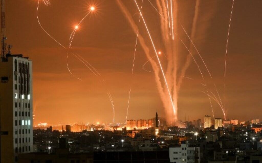 Hamas rockets light up the night sky as they are fired towards Israel from Beit Lahia in the northern Gaza Strip on May 14, 2021, while Israeli Iron Dome interceptors rise to meet them (Photo by MOHAMMED ABED / AFP)