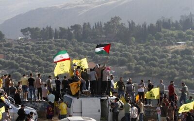 Supporters of Lebanon's Hezbollah lift its flags (C) alongside those of Iran (L) and Palestine, during an anti-Israel protest in the southern Khiam area by the border with Israel, facing the northern Israeli town of Metula, on May 14, 2021. (Photo by Mahmoud ZAYYAT / AFP)