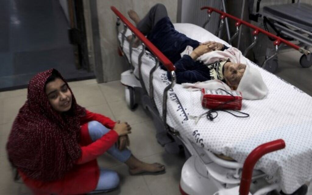 A Palestinian girl sits on the floor next to her wounded grandmother at Al-Shifa Hospital, after an Israeli air strike struck al-Shati Refugee Camp in Gaza City early on May 15, 2021.(Photo by MAHMUD HAMS / AFP)
