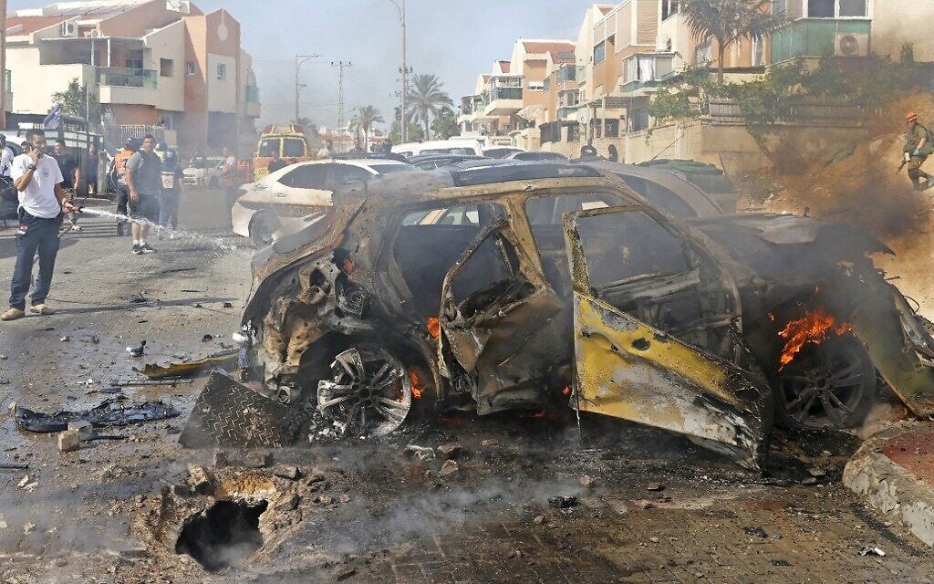 A firefighter extinguishes a burning vehicle in the southern Israeli city of Ashkelon following a rocket attack fired from the Gaza Strip, on May 16, 2021. (JACK GUEZ / AFP)