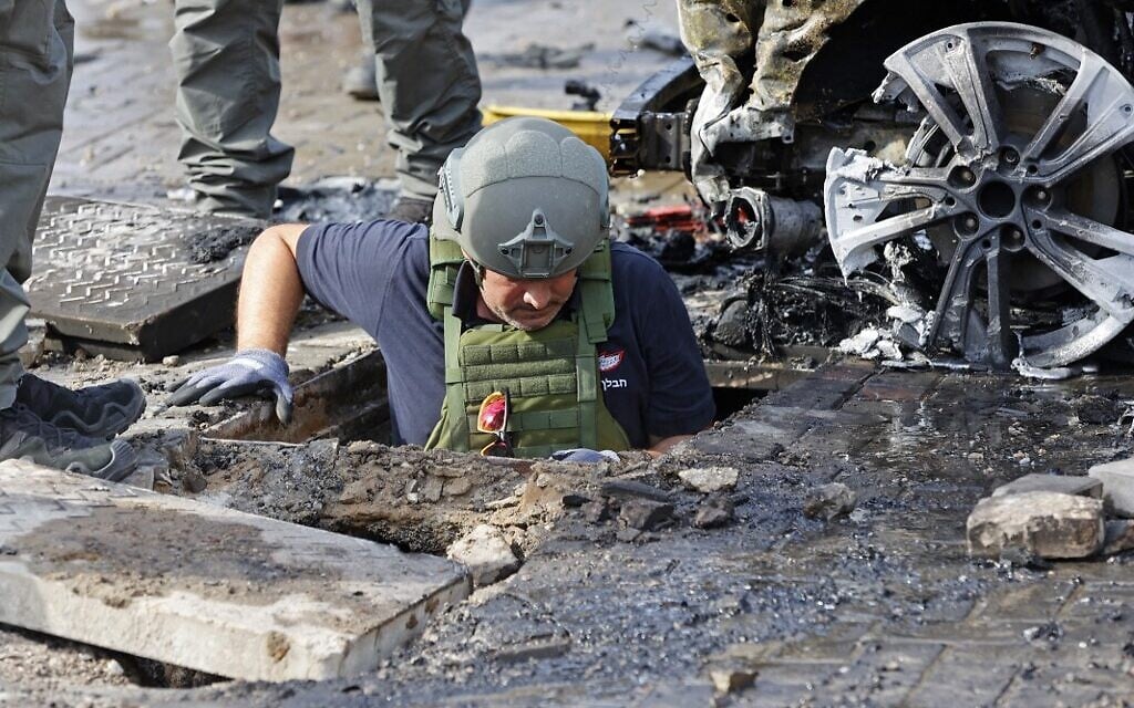 A member of Israeli security forces inspects a crater in the southern Israeli city of Ashkelon following a rocket attack fired from the Gaza Strip, on May 16, 2021. (JACK GUEZ / AFP)