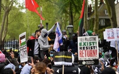Pro-Palestinian activists and supporters burn an Israeli flag as they demonstrate in support of the Palestinian cause outside the Israeli Embassy in central London on May 22, 2021. (Photo by JUSTIN TALLIS / AFP)