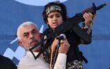 Hamas chief Yahya Sinwar holds the child of an Al-Qassam Brigades member who was killed in the recent fighting with Israel, during a rally in Gaza City on May 24, 2021. (Emmanuel Dunand / AFP)