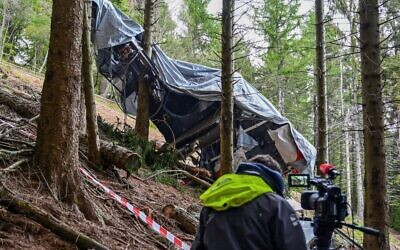 A view shows a journalist working by a cable car's wreckage covered with a tarpaulin on May 26, 2021 on the slopes of the Mottarone peak above Stresa, Piedmont, three days after a crash that killed 14 (MIGUEL MEDINA / AFP)