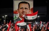 Syrians wave national flags and carry a large portrait of their president as they celebrate in the streets of the capital Damascus, a day after an election set to give the current President Bashar Assad a fourth term, on May 27, 2021 (LOUAI BESHARA / AFP)