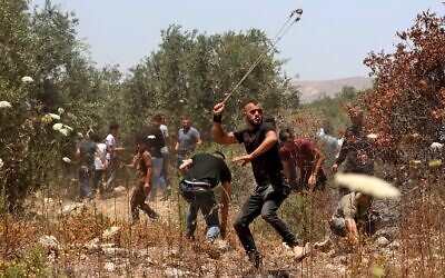 Palestinian protesters use slingshots to hurl stones at Israeli security forces amid clashes in the village of Baita, south of Nablus, in the West Bank on May 28, 2021. (JAAFAR ASHTIYEH / AFP)
