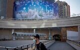 An Iranian walks across a campaign banner hanging on the facade of a building in the capital Tehran on May 28,  2021. - Iran's presidential election campaign officially kicked off, without fanfare and in an atmosphere of indifference as many say the result is a foregone conclusion. ( AFP)