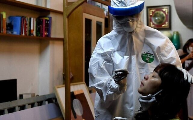 In this file photo taken on March 30, 2020, a health worker, wearing protective clothing amid concerns of the spread of the COVID-19 coronavirus, conducts a swab test on a woman in her house in Hanoi, Vietnam. (Nhac NGUYEN / AFP) In this file photo taken on March 30, 2020, a health worker, wearing protective clothing amid concerns of the spread of the COVID-19 coronavirus, conducts a swab test on a woman in her house in Hanoi, Vietnam. (Nhac NGUYEN / AFP)