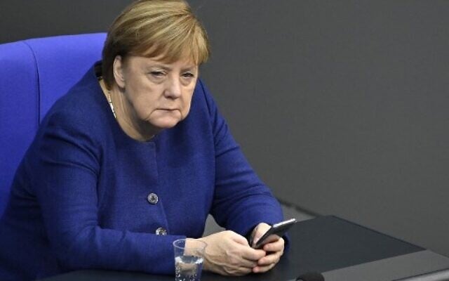 German Chancellor Angela Merkel uses her mobile phone during a debate at the Bundestag in Berlin, December 8, 2020. (MACDOUGALL/AFP) German Chancellor Angela Merkel uses her mobile phone during a debate at the Bundestag in Berlin, December 8, 2020. (MACDOUGALL/AFP)