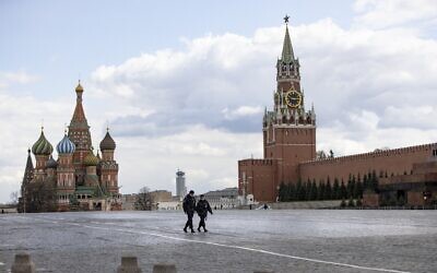 Two police officers patrol an almost empty Red Square, with St. Basil's Cathedral, center, and Spasskaya Tower in Moscow, Russia, April 20, 2020 (AP Photo/Alexander Zemlianichenko)
